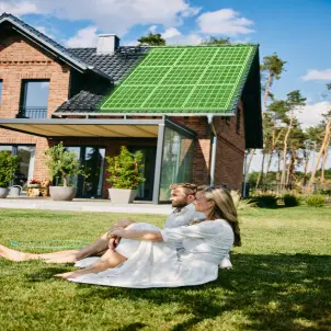 Ein Paar sitzt vor einem Haus mit PV - Anlage