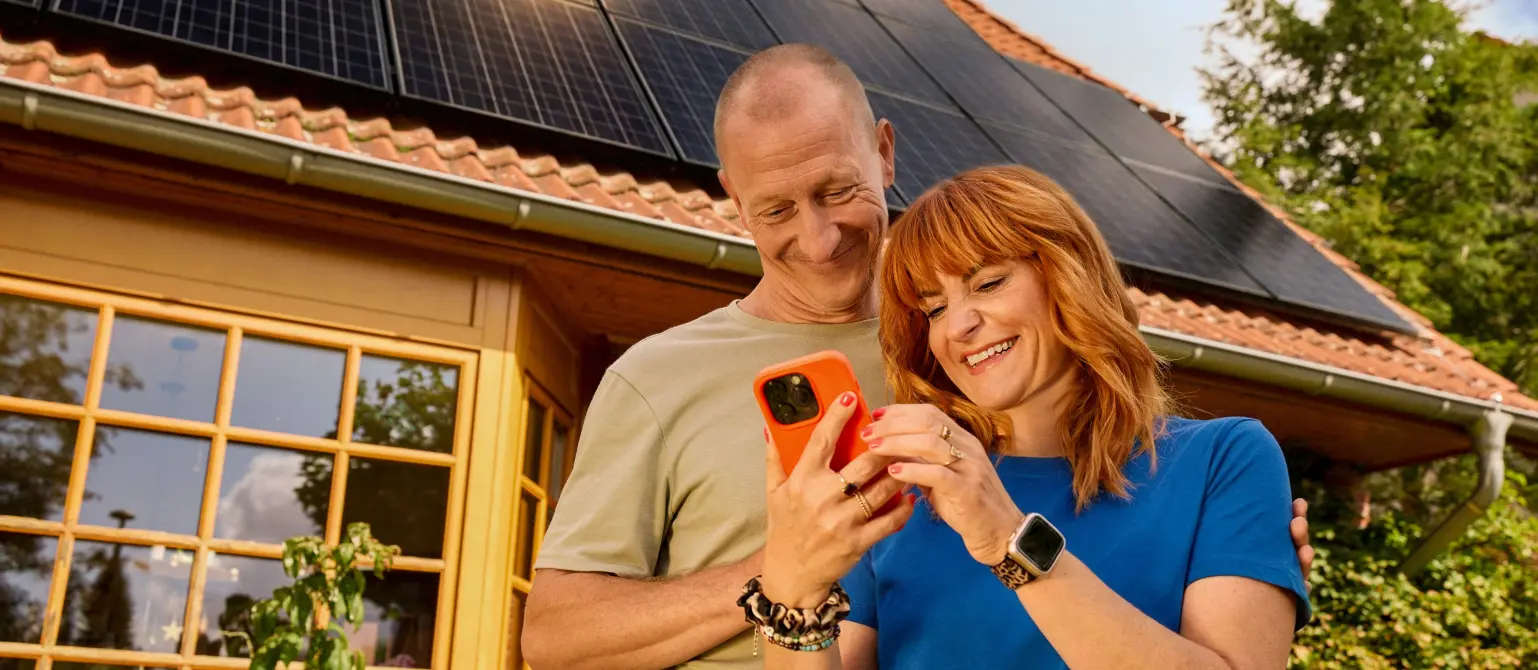 Ein Paar steht vor einem Einfamilienhaus mit Solaranlage auf dem Dach