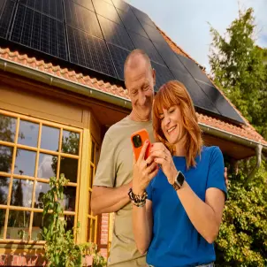 Ein Paar steht vor einem Einfamilienhaus mit Solaranlage auf dem Dach