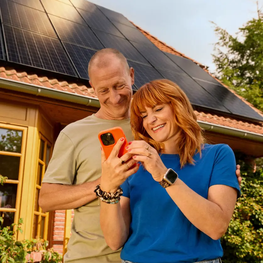 Ein Paar steht vor einem Einfamilienhaus mit Solaranlage auf dem Dach