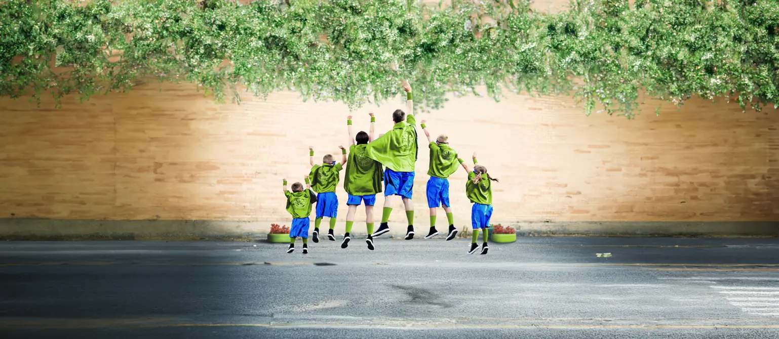 Familie, die als Superhelden in grün-blau gekleidet, sind von hinten zu sehen und machen eine Superman-Pose.