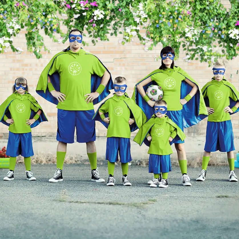 Familie mit vier Kindern ist in grün-blau als Superhelden verkleidet und maskiert.