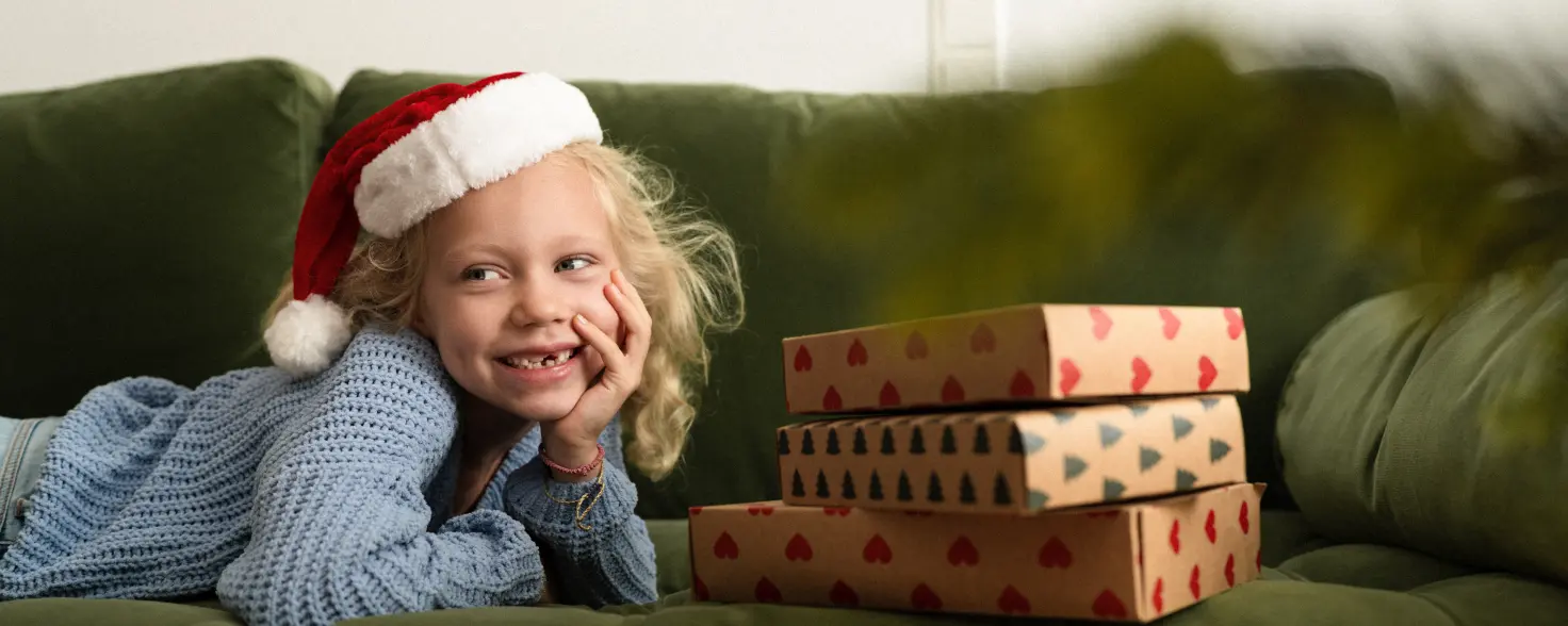 Kleines Mädchen mit Geschenken liegt auf der Couch