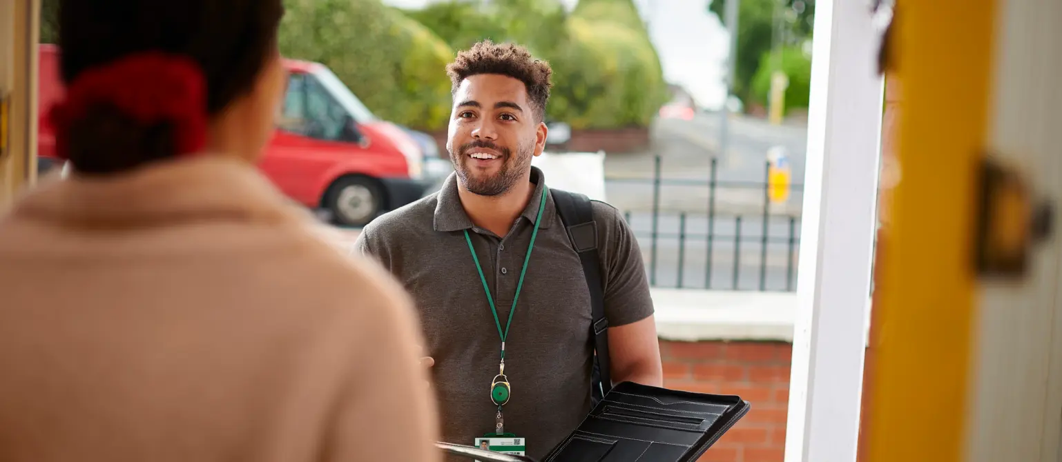 Ein Berater im Außendienst von Energie Brandenburg berät eine Kundin an der Haustür zu Energiedienstleistungen.