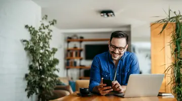 Glücklicher Mann schaut auf seinen Laptop