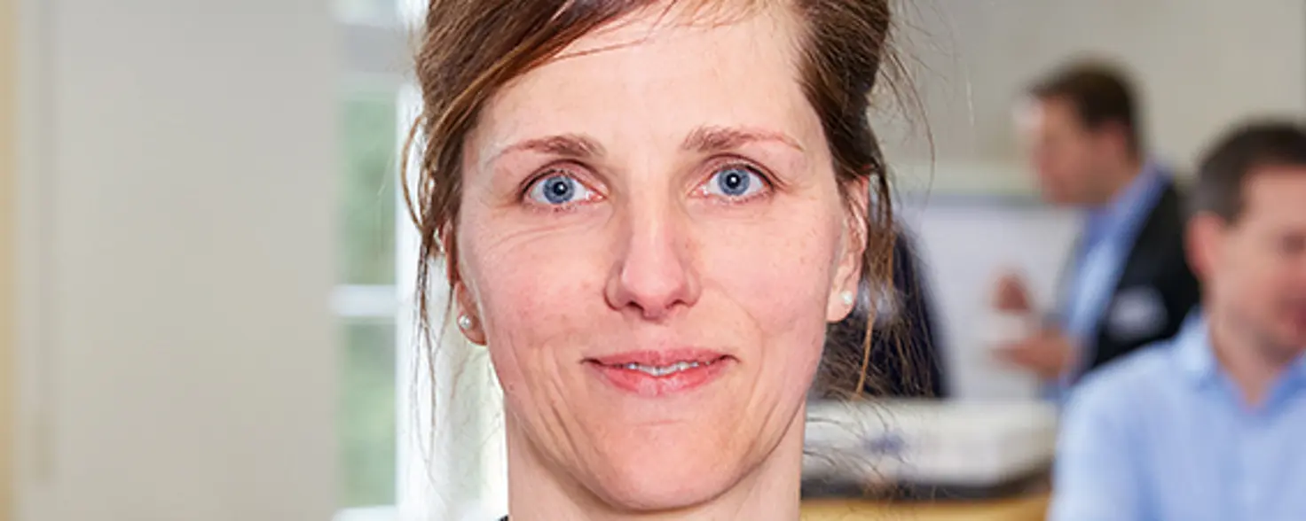 Porträtfoto: Antje Weber trägt ein gestreiftes Hemd und lächelt in die Kamera