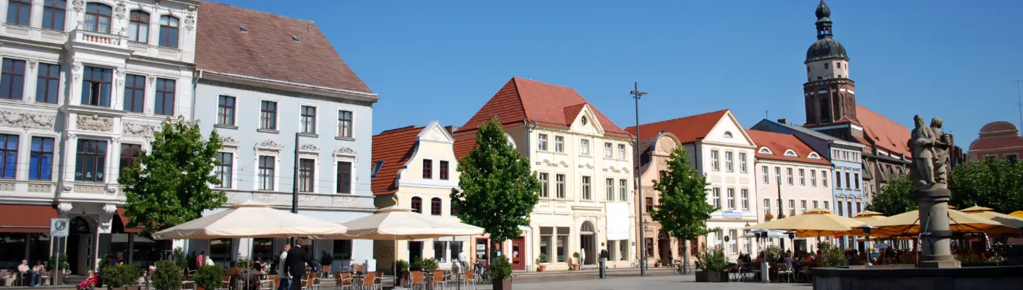 Der Marktplatz in Cottbus mit einem Springbrunnen in der Mitte und drumherum mehrstöckige Häuser.