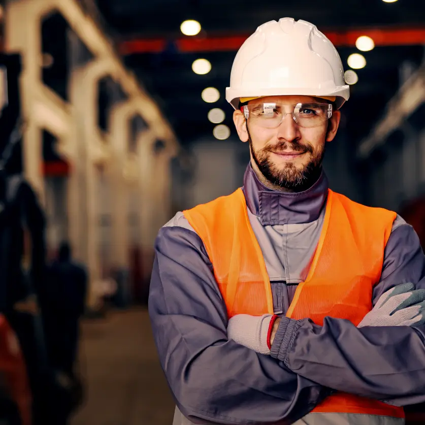 Ein Mann mit Helm, Schutzbrille und Arbeitsweste schaut in die Kamera