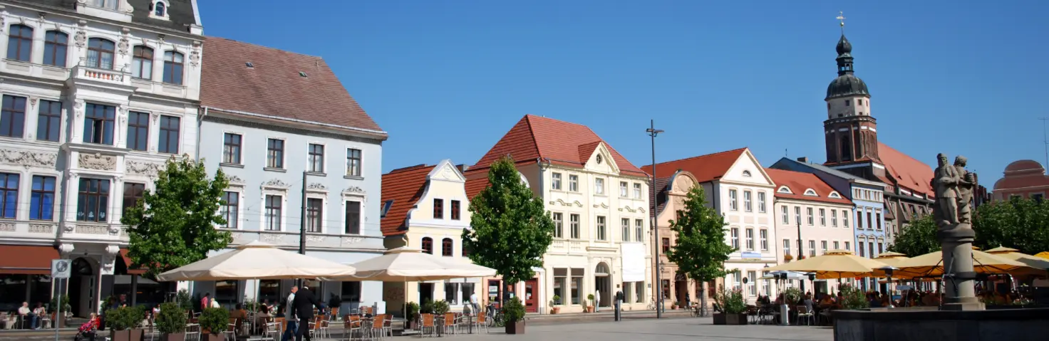 Der Marktplatz in Cottbus mit einem Springbrunnen in der Mitte und drumherum mehrstöckige Häuser.