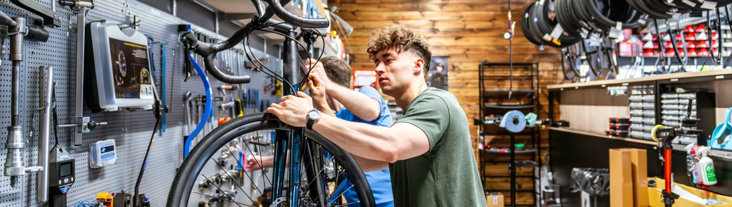 Ein jungen Mann repariert ein Fahrrad in einer Werkstatt