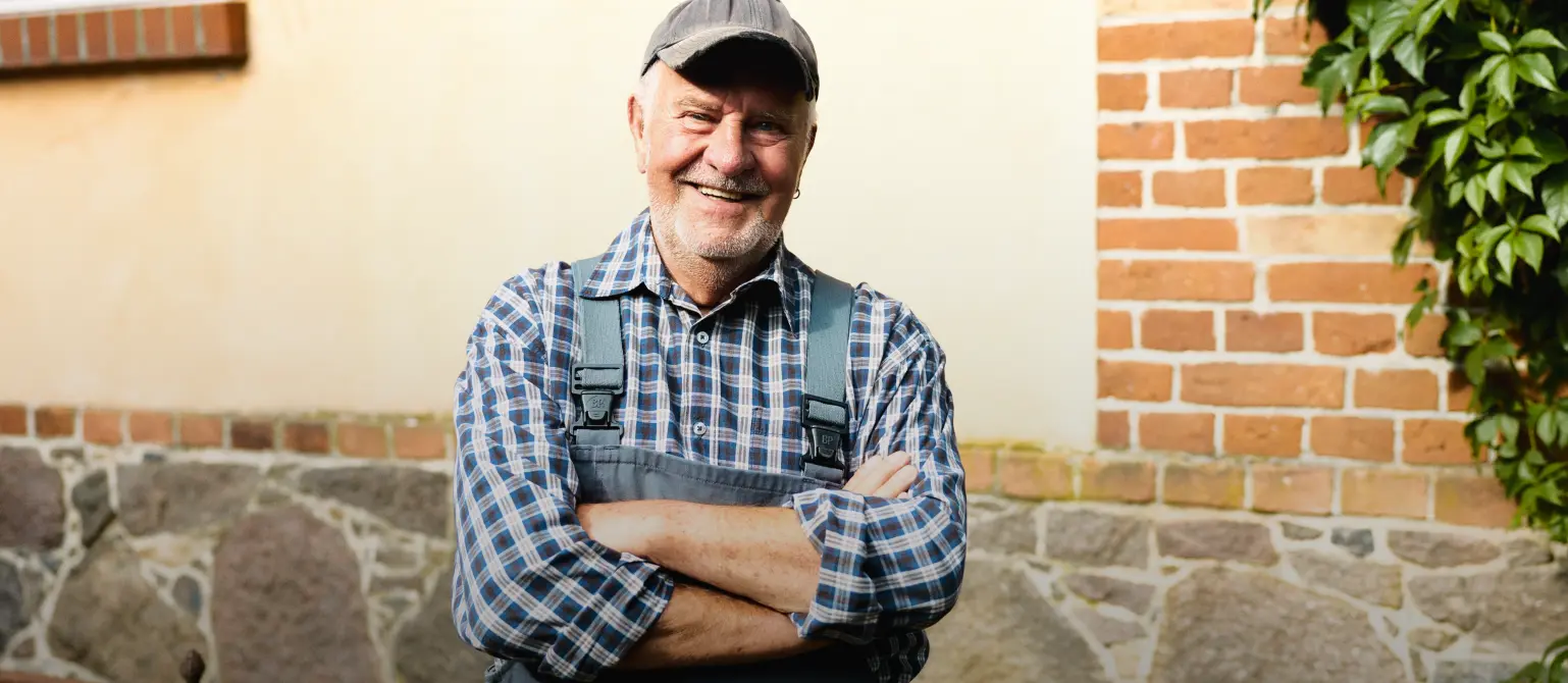 Handwerker schaut freundlich in die Kamera in einem karierten Hemd und Arbeitshose