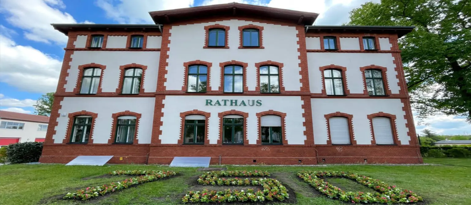 Rathaus der Brandenburger Gemeinde Großbeeren. Davor bilden Blumen die Zahl 750.