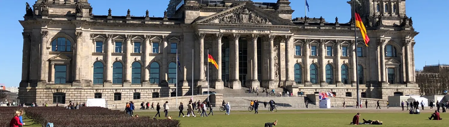 Das beflaggte Reichstagsgebäude in Berlin, Sitz des Deutschen Bundestags, bei Sommerwetter.