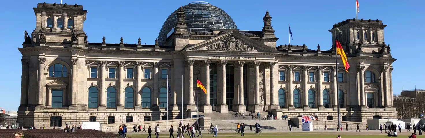 Das beflaggte Reichstagsgebäude in Berlin, Sitz des Deutschen Bundestags, bei Sommerwetter.
