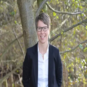 Kerstin Hoppe, Bürgermeisterin der Gemeinde Schwielowsee, in schwarzem Blazer und weißer Bluse. Im Hintergrund Bäume.
