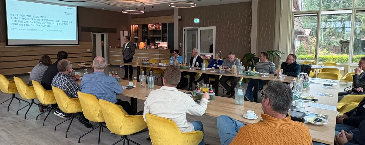 Teilnehmende beim Bürgermeisterstammtisch von Energie Brandenburg in Kyritz sitzen u-förmig um einen Tisch und folgen dem Vortragenden Dr. Jens Horn.