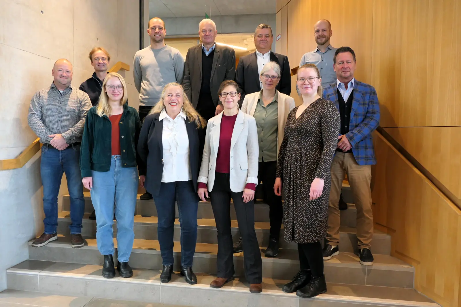 KWPconnect: Gruppe von elf Personen steht für ein Teamfoto auf einer Treppe in einem modernen Innenraum.