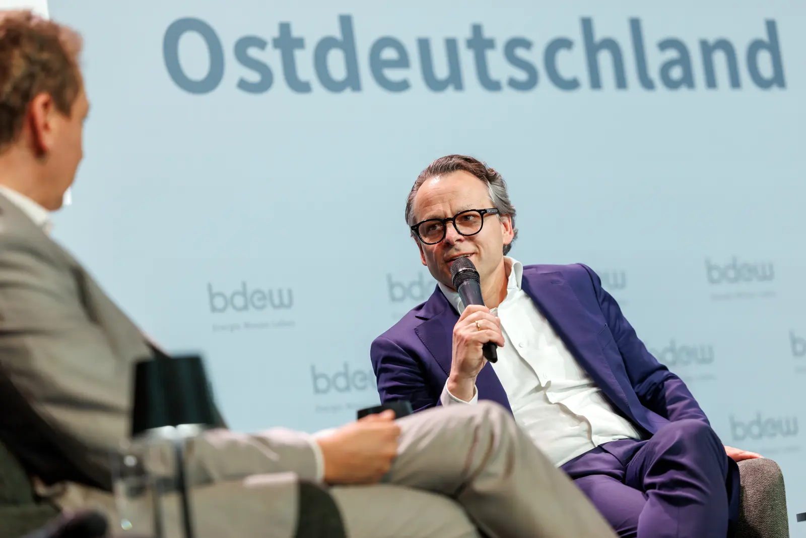 Person sitzt in einer Gesprächssituation und diskutiert als Geschäftsführer von Energie Brandenburg auf dem Podium.