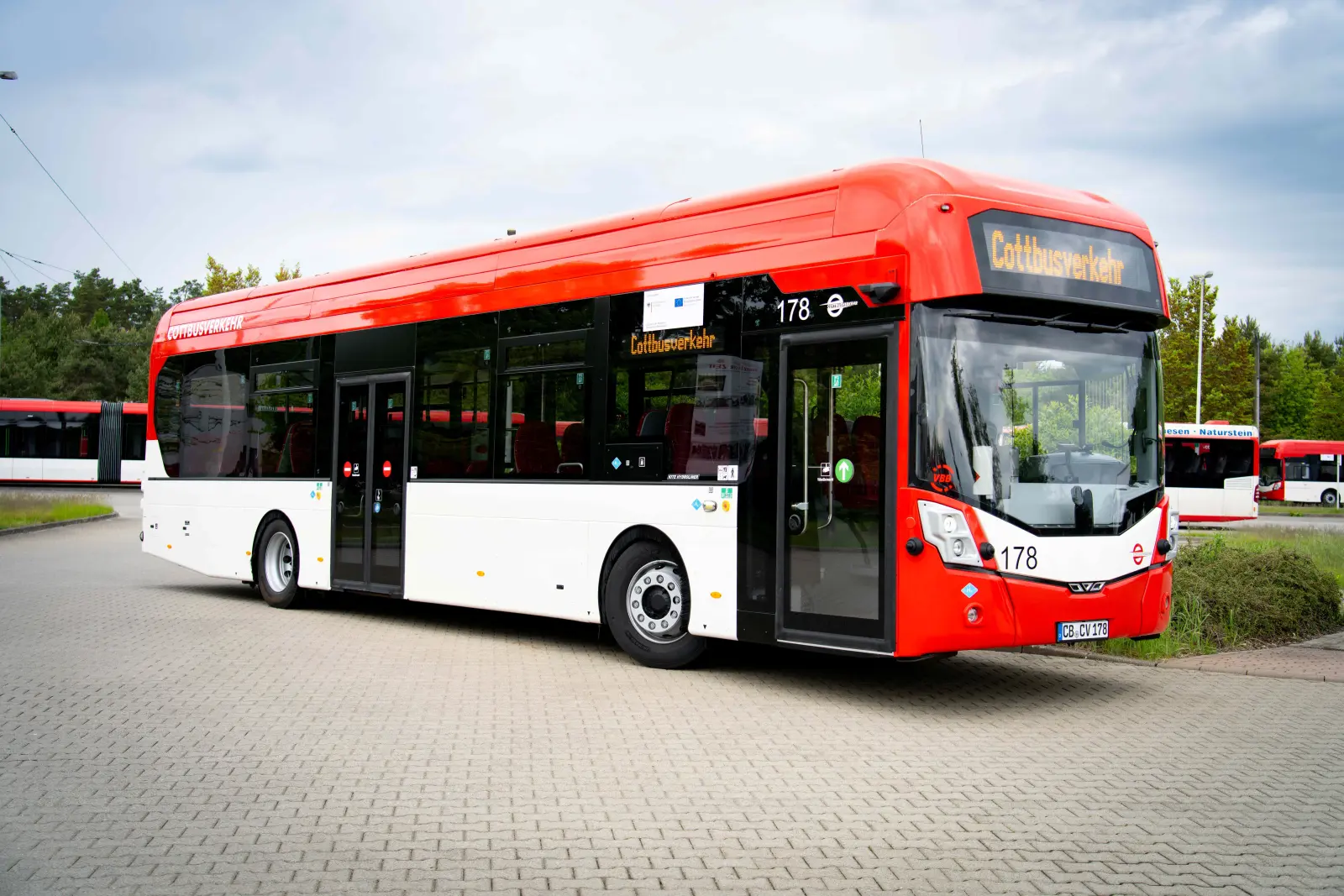 Ein rot-weißer Nahverkehrsbus steht auf einem Parkplatz. Er ist als Bus, der mit Wasserstoff betrieben wird, gekennzeichnet.