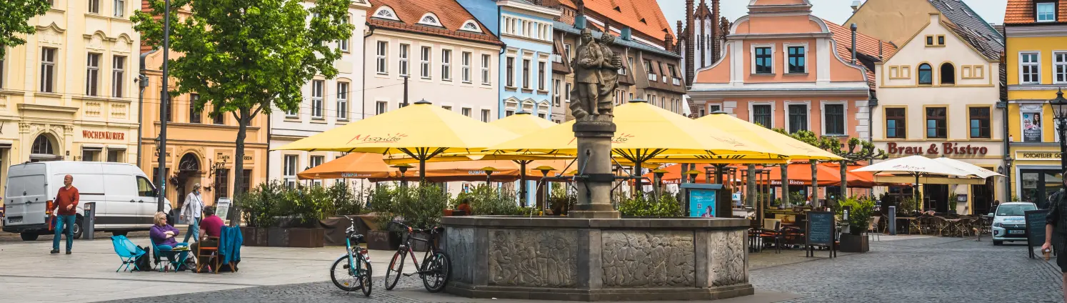 Der Marktplatz von Cottbus mit Fachwerkhäusern und einem Brunnen.