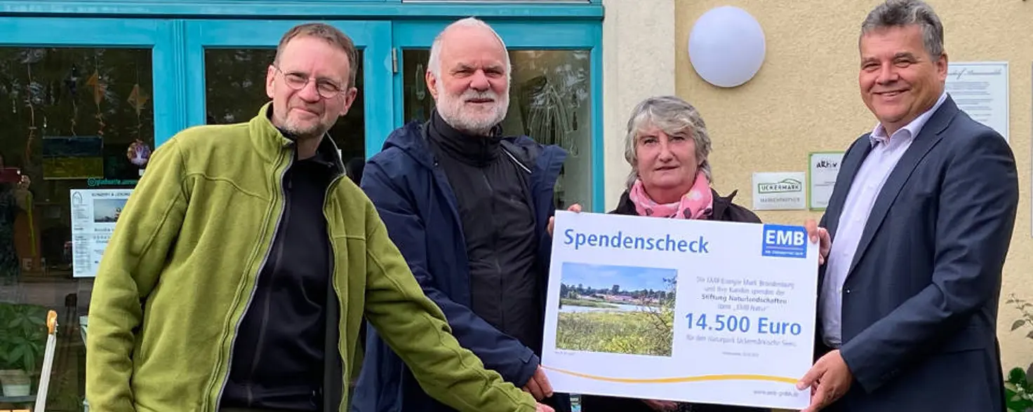 EMB Natur: Vier Personen halten einen Spendenscheck der Energie Brandenburg über 14.500 Euro in den Händen und schauen in die Kamera