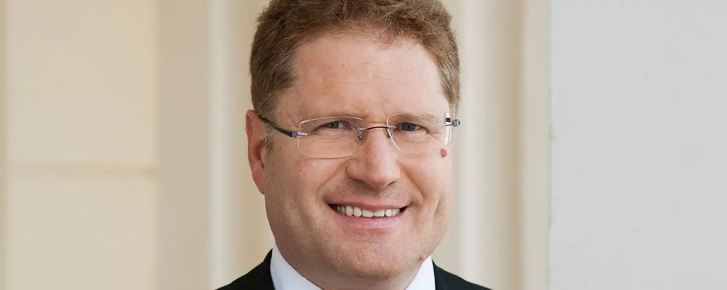 Porträtfoto: Dr. Patrick Graichen, Geschäftsführer von Agora Energiewende, trägt Anzug, Brille und lächelt in die Kamera.