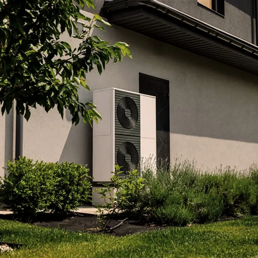 Modernes Haus mit Wärmepumpe im grünen Garten