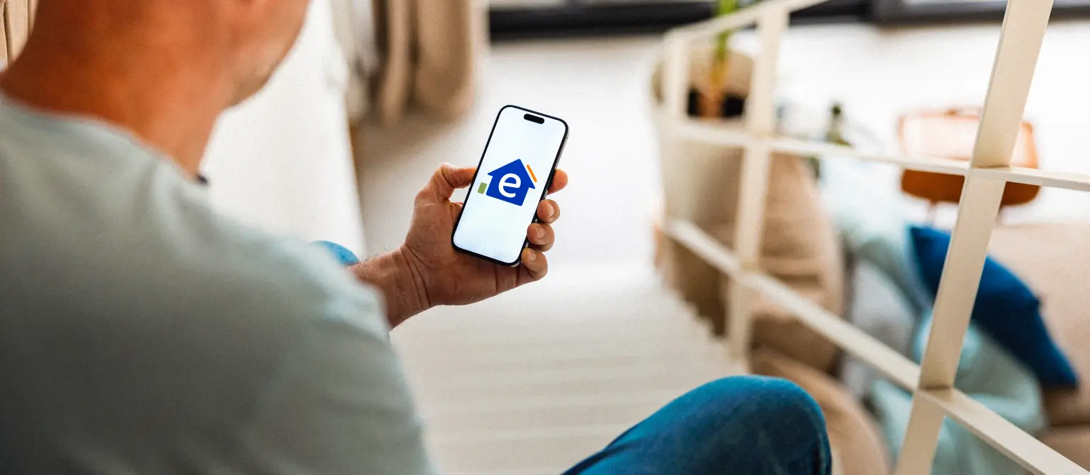 Blick über die Schulter einer Person auf das Handy auf dem das Logo von Energie Brandenburg ist.