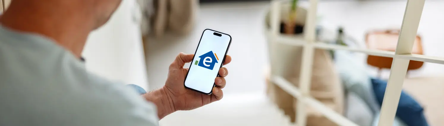 Blick über die Schulter einer Person auf das Handy auf dem das Logo von Energie Brandenburg ist.