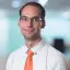 Porträtfoto Tom Beier von Energie Brandenburg in weißem Hemd mit orangefarbenen Schlips.