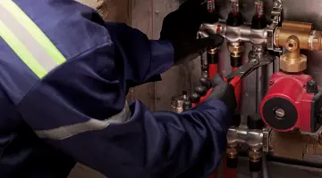 Ein Installateur wird von hinten gezeigt, wie er etwas repariert