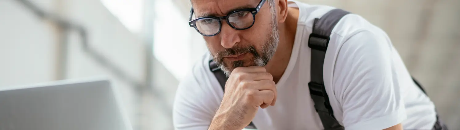 Newsletter Energie Brandenburg kompakt: Installateur mit Brille liest Newsletter am Laptop in der Werkstatt.