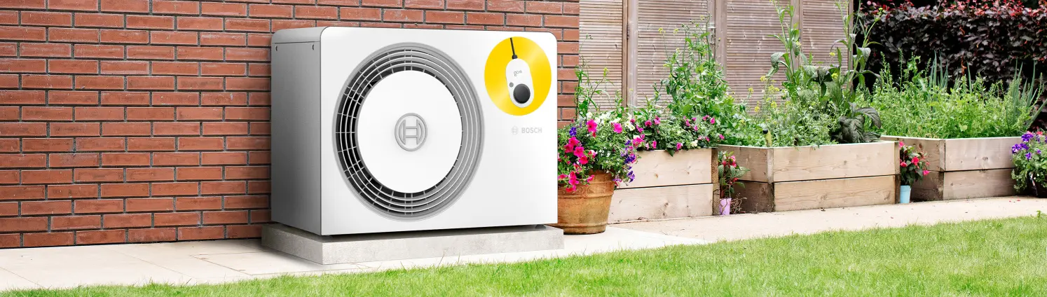 Eine Bosch-Wärmepumpe steht im Garten neben Pflanzenkübeln