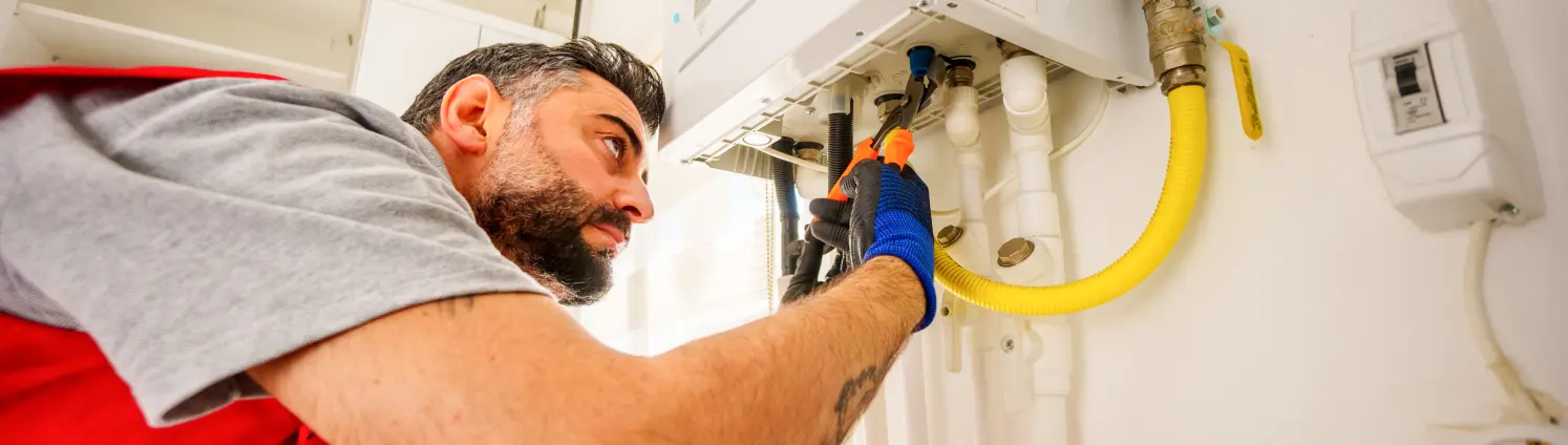 Ein Heizungsinstallateur arbeitet an einer Gasheizung