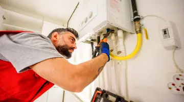 Ein Heizungsinstallateur arbeitet an einer Gasheizung