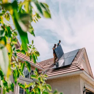 Zwei Monteure installieren PV-Module auf dem Dach eines Einfamilienhauses