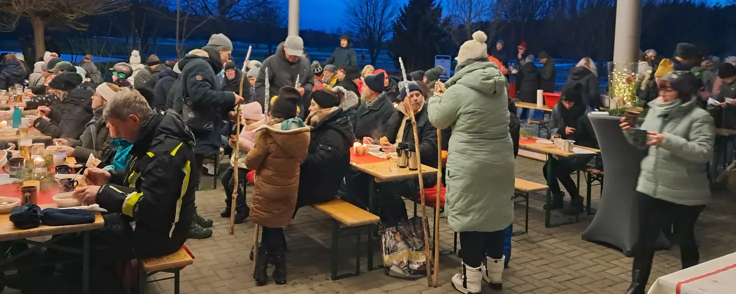 Die Menschen wärmen sich unter einem Zelt mit warmen Getränk oder einer Gulaschsuppe auf.