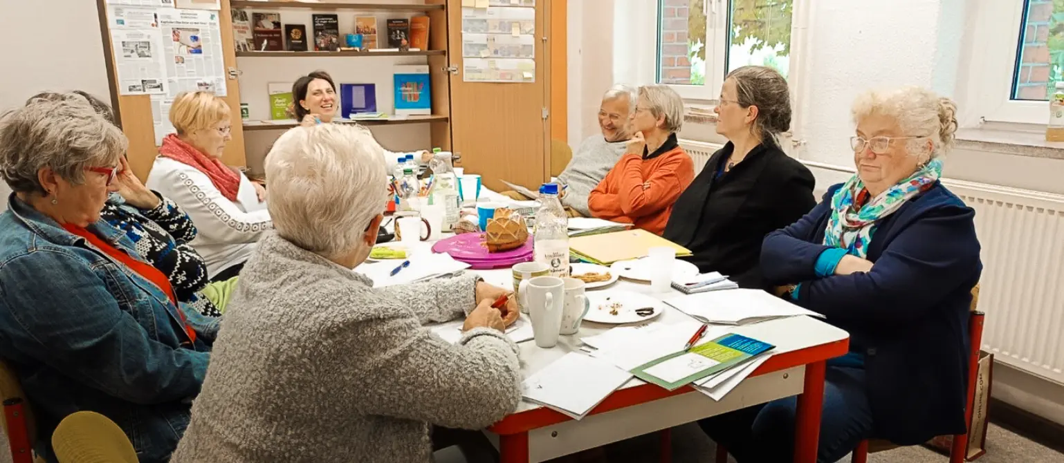 Die Bewohnerschaft des Wohnprojekts sitzt an einem Tisch und sie tauschen Ideen aus.