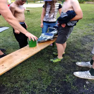 Mehrere Mitglieder der Jugendfeuerwehren testen Rettungszubehör der Feuerwehr auf einer Bierbank im Freien.