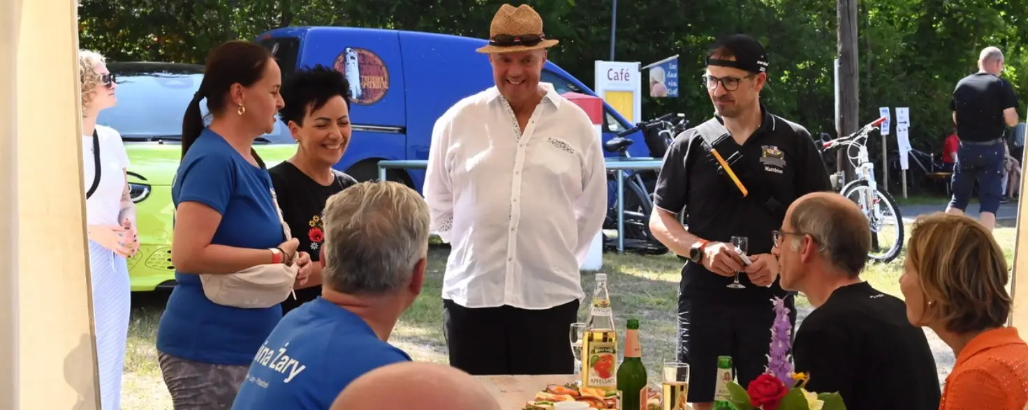 Eine Runde von Teilnehmenden der Wasserfestspiele Neuhausen/Spree unterhält sich angeregt an einem Biertisch.