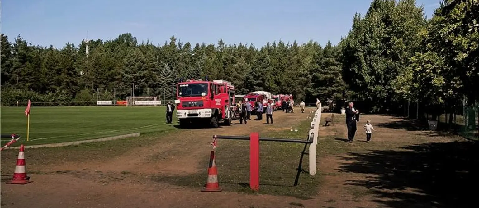 Feuerwehrwagen auf großer Wiese.