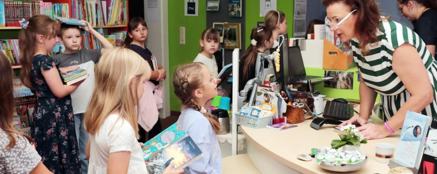 Brandenburger Lesesommer: Kinder mit Büchern stehen an der Buchausgabe einer Bibliothek Schlange.