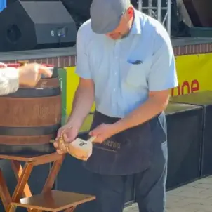 Heimatfest Burg: Mann mit Schürze und Schiebermütze sticht ein Fass Bier an.