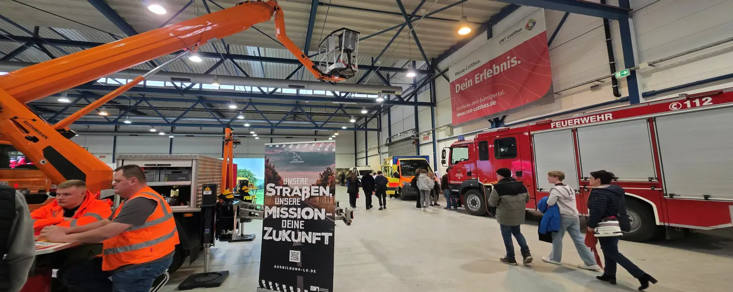 Impuls-Messe Cottbus: Besucherinnen und Besucher bewundern ein Einsatzfahrzeuge der Feuerwehr und eine Hubarbeitsbühne.