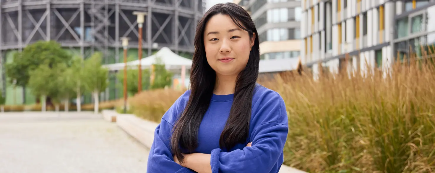 Auszubildende im blauen Oberteil steht mit verschränkten Armen vor dem Hauptsitz der GASAG-Gruppe in Berlin Schöneberg.