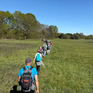 Eine Gruppe von Menschen läuft in einer Reihe auf einem schmalen Feldweg.