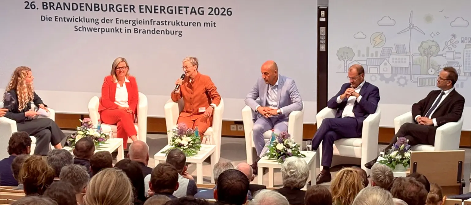 Sechs Personen sitzen auf einer Bühne und unterhalten sich in einem Halbkreis.