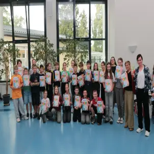 Kinder der sechsten Klasse halten eine Urkunde für den ersten Platz hoch.
