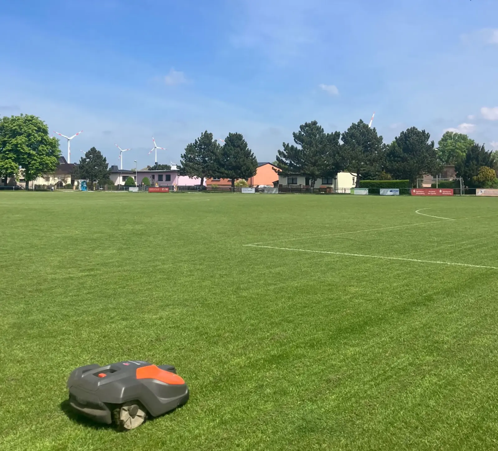 Ein Mähroboter fährt über die große Fußballfläche