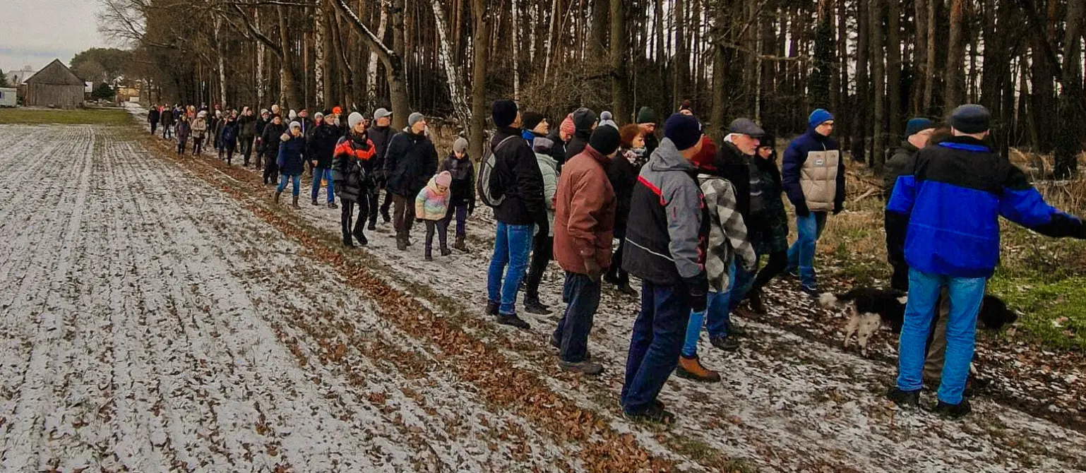 Neujahrswanderung in Drieschnitz-Kahsel: Wandergruppe in Winterkleidung auf einem Feldweg am Waldrand.